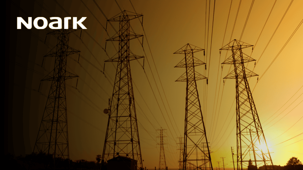Against the vibrant orange sky at sunset, power lines and towers stretch into the horizon. The word "Noark" adorns the top left corner, subtly highlighting the importance of disconnect switches in ensuring seamless energy flow and safety.